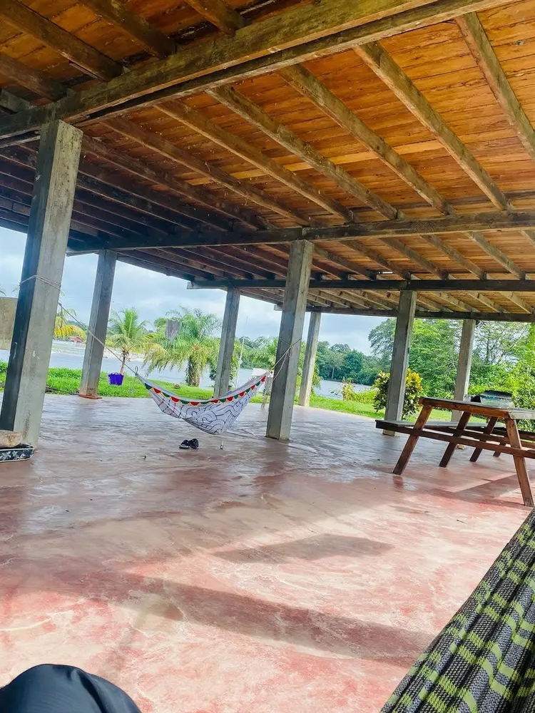 Open eetzaal met hangmatten en uitzicht op de rivier